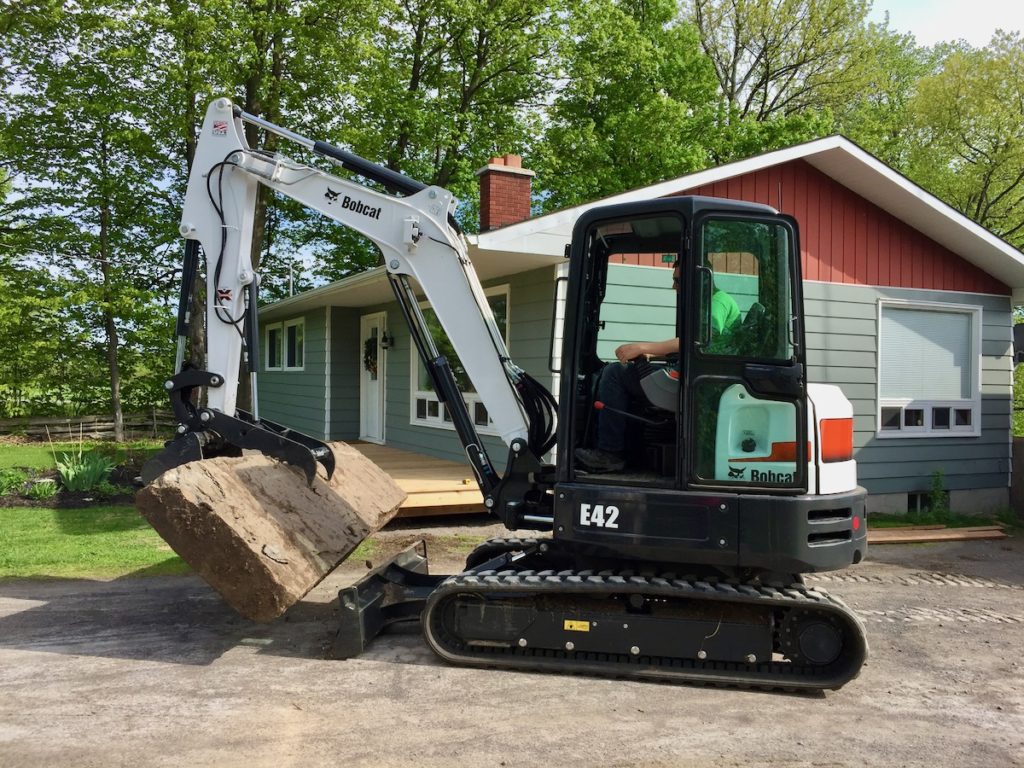 mini excavator lifting large stone