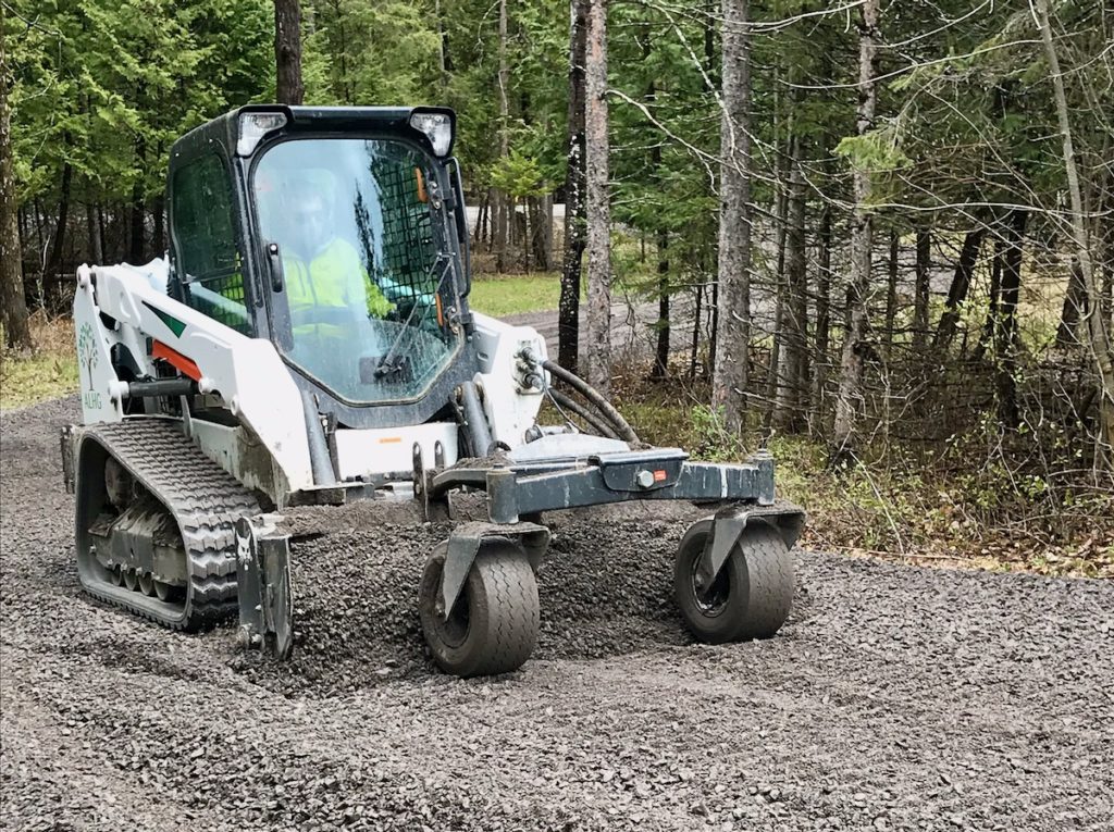 Skidsteer with harley rake grading driveway